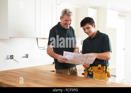 Carpenter And Apprentice Installing Luxury Fitted Kitchen Stock Photo