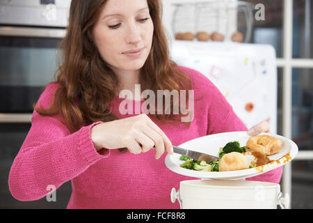 Woman Scraping Food Leftovers Into Garbage Bin Stock Photo