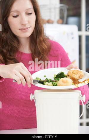 Woman Scraping Food Leftovers Into Garbage Bin Stock Photo