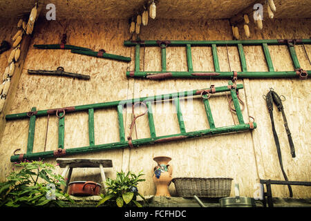 The wall of shed with ladders, various tools and dried corn. Village theme. Farm yard. Stock Photo