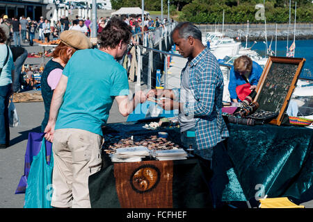 Couple shopping in a stand in negotiations with the seller at a local market in Hondarribia marina. Basque Country, Spain. Stock Photo