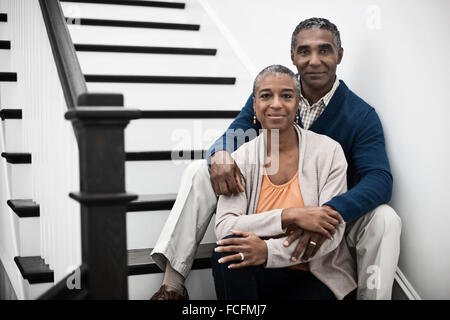 A mature couple, man and woman, sitting on the stairs together at home. Stock Photo