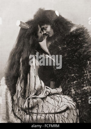 The Maori method of greeting by pressing noses.  One girl wears a flax cloak and a huia feather, the badge of rank, in her hair, the other a cloak of feathers of a flax foundation. After a 19th century photograph. Stock Photo