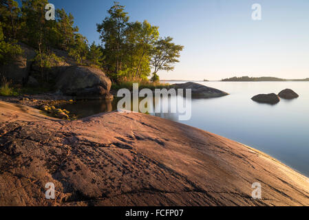 Rocky coast in a small bay of the Yxlan island in the archipelago near Stockholm in Sweden in the warm evening light Stock Photo