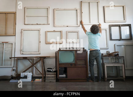 Loft decor. A man hanging framed picture canvases on a wall. Stock Photo