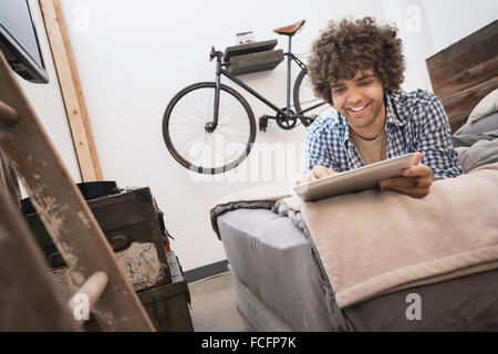 Loft living. A bicycle hanging on a wall. A man using a digital tablet. Stock Photo