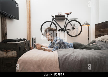 Loft living. A bicycle hanging on a wall. A man using a digital tablet. Stock Photo