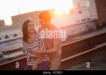 A couple on a rooftop terrace at dusk laughing Stock Photo