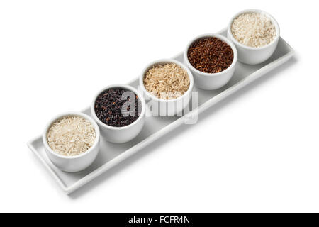 Bowls with different types of raw rice on white background Stock Photo