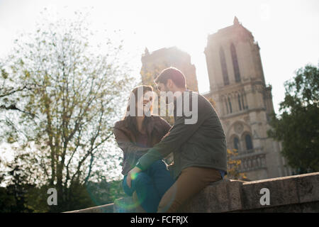 A couple in a romantic mood, side by side with arms around each other outside Notre Dame Cathedral in Paris.