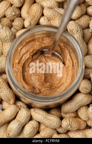 Jar of peanut butter among peanuts Stock Photo