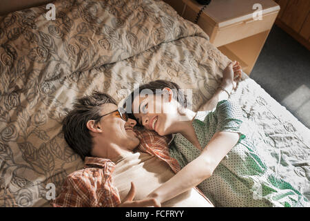 A young couple lying side by side on top of the bed in a motel room. Stock Photo