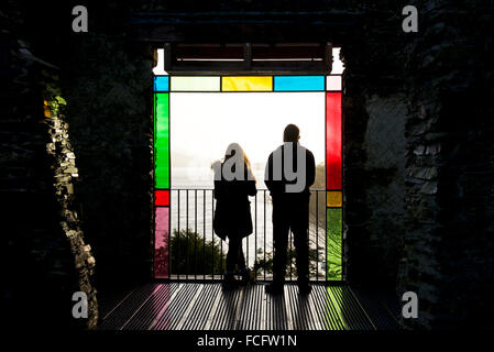 Couple standing at window of renovated Claife Station, enjoying the view of Lake Windermere, Lake District, Cumbria, England UK Stock Photo