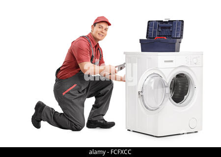 Young repairman fixing a washing machine and looking at the camera isolated on white background Stock Photo