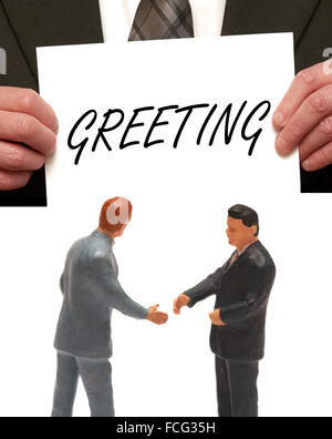 Greeting concept 2 miniature figurines in suits shaking hands Stock Photo