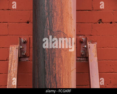 Rusted metal post against painted red brick wall in downtown Montreal, Quebec, Canada. Stock Photo