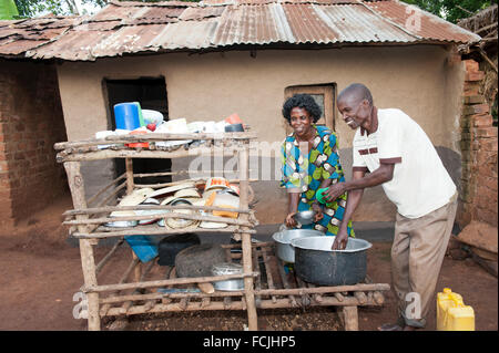 Ugandan couple working together to clean dishes in a rural village. Uganda. Stock Photo