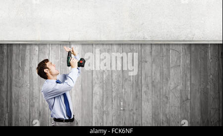 Young businessman using drill to fix banner Stock Photo