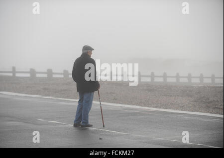 In thick fog, an old man stands on the promenade looking out to sea in Littlehampton, West Sussex, England.