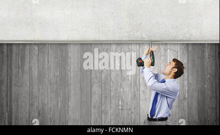 Young businessman using drill to fix banner Stock Photo