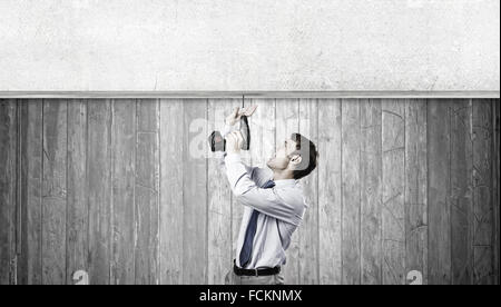 Young businessman using drill to fix banner Stock Photo