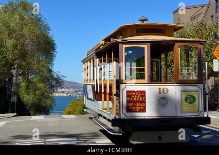Cable car on Hyde Street at junction with Lombard Street, with distant view of Alcatraz Island, San Francisco, California, USA