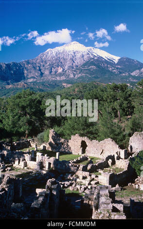 Ruins of the Ancient Greek and Roman City of Phaselis, with the Snow-Capped Peak of Olympos National Park and the Bey Mountains part of the Taurus Range,  Kemer, Antalya, Turkey. Stock Photo