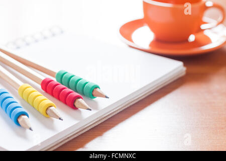 Pencils on open blank white notebook with coffee cup on the desk, stock photo Stock Photo