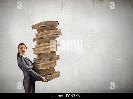 Young businesswoman carrying pile of old books Stock Photo - Alamy