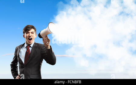 young businessman in black suit screaming into megaphone Stock Photo