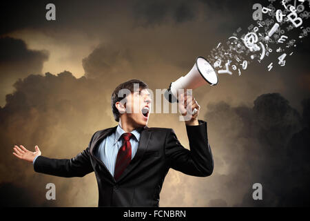 young businessman in black suit screaming into megaphone Stock Photo