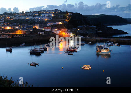Mevagissey Harbour at Dusk, boats moored in the harbour, lights from street lamps and houses ioverlooking the quay, Cornwall, Au Stock Photo