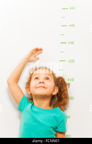 Girl measure height with hand looking up Stock Photo