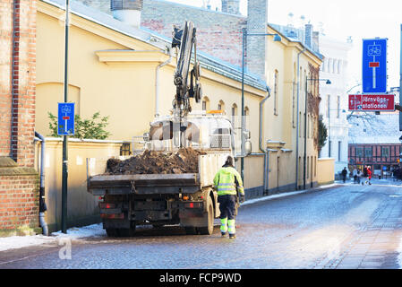 Lund, Sweden - January 21, 2016: A worker has just collected some soil from the other side of a wall and walk beside his truck t Stock Photo