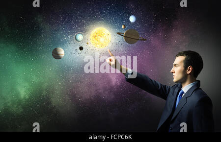 Young businessman and planets of space spinning around Stock Photo