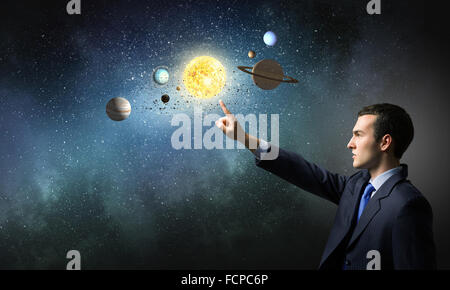 Young businessman and planets of space spinning around Stock Photo