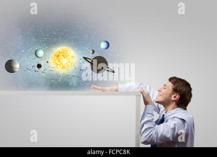 Young businessman and planets of space spinning around Stock Photo