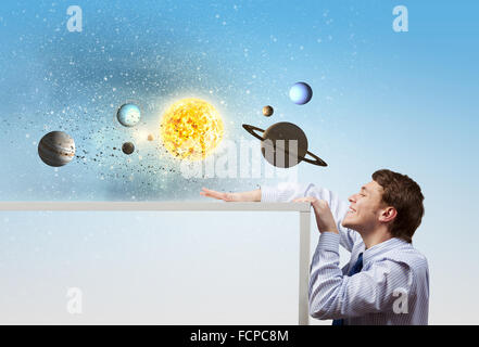 Young businessman and planets of space spinning around Stock Photo