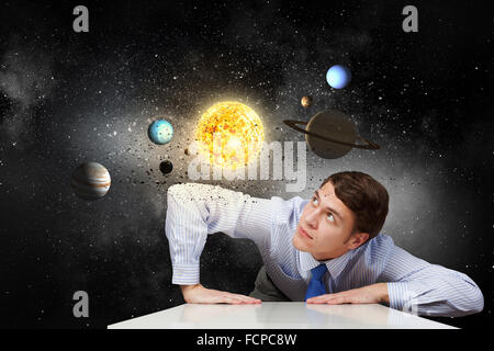 Young businessman and planets of space spinning around Stock Photo