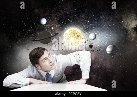 Young businessman and planets of space spinning around Stock Photo