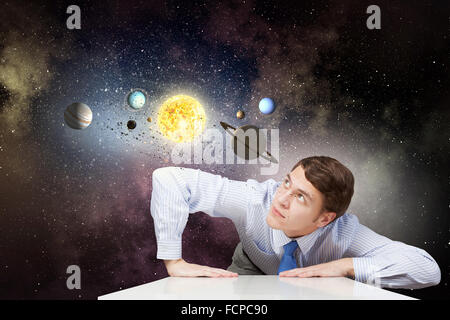 Young businessman and planets of space spinning around Stock Photo