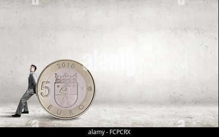 Young businessman rolling huge five euro coin Stock Photo