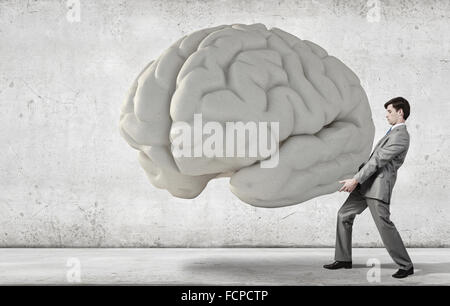 Businessman making effort to carry huge human brain Stock Photo