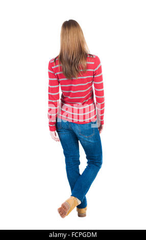 back view of standing young beautiful blonde woman in jeans. girl watching. Rear view people collection. backside view of person. Isolated over white background. Throwing his legs blonde in a striped red sweater looks ahead. Stock Photo