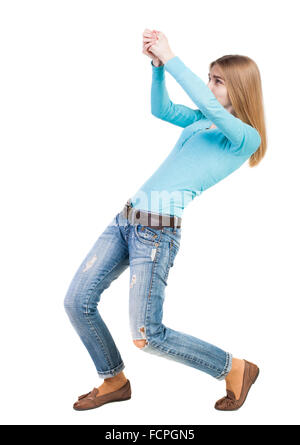 back view of standing girl pulling a rope from the top or cling to something. girl watching. Rear view people collection. backside view of person. Isolated over white background. Strongly leaning back, she pulls the top rope. Stock Photo