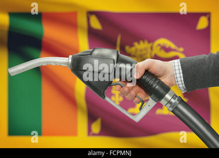 Fuel pump nozzle in hand with flag on background - Sri Lanka Stock Photo