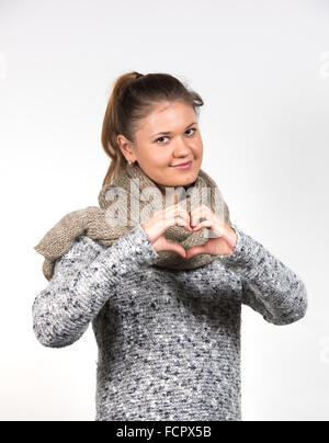young woman  wearing winter clothes, shows love sign Stock Photo