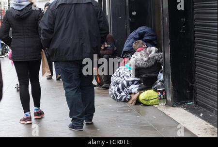 Brighton UK 24th January 2016 - Shoppers walk past some rough sleepers on the streets of Brighton today . A shrine with tributes in memory of the homeless who have died on the streets of Brighton has been created at the city centre clock tower .  Credit:  Simon Dack/Alamy Live News Stock Photo