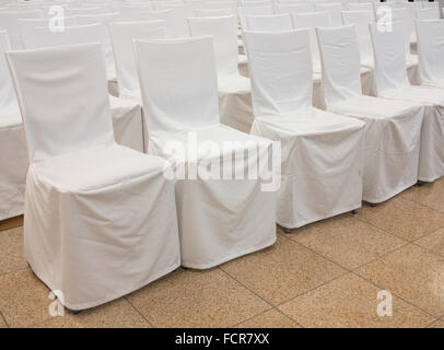 Chairs with white fabric covers in a row Stock Photo