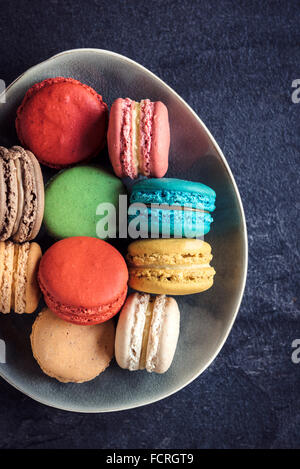 Sweet and colorful macaroon cookies in the plate on dark background,selective focus Stock Photo
